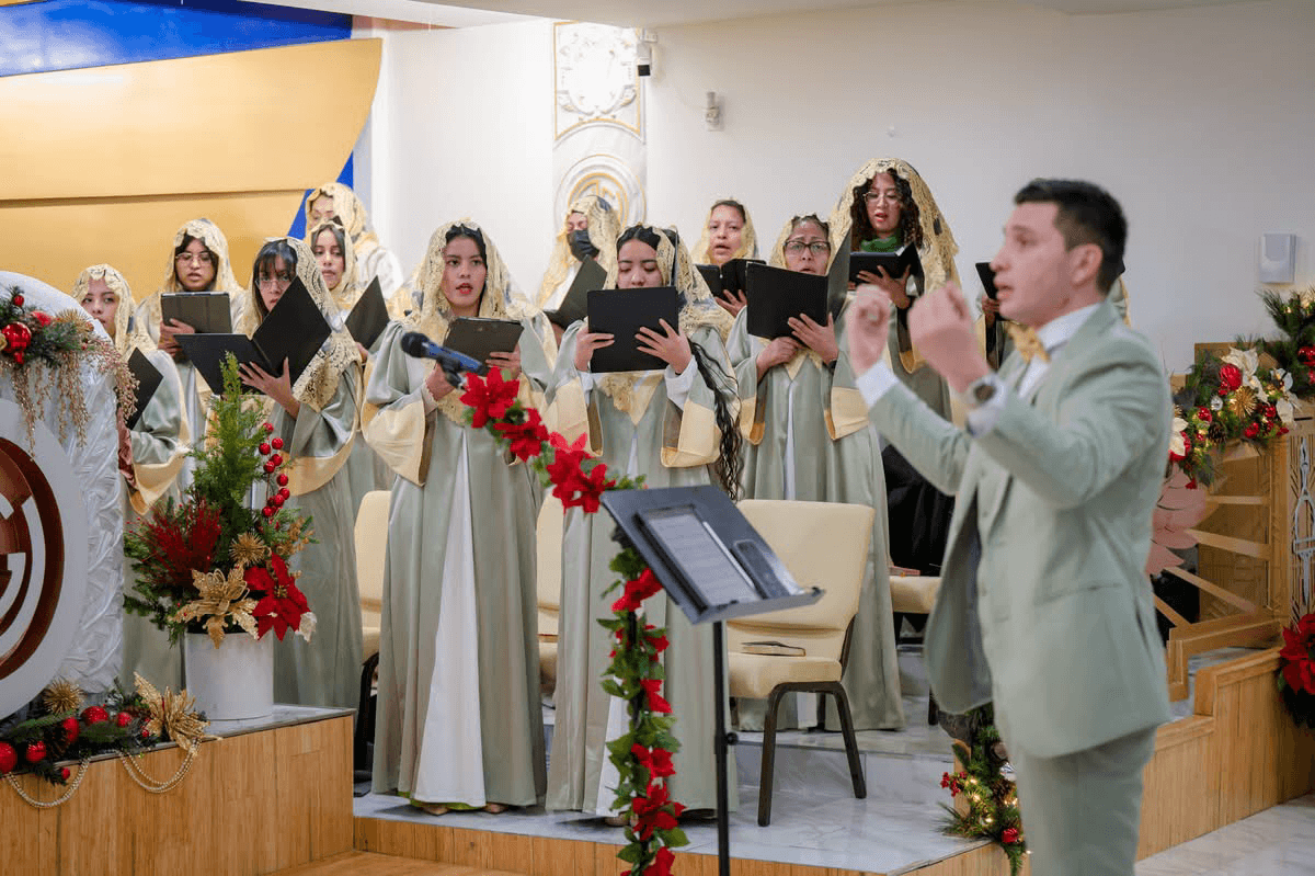 A choir director conducting in a sage-green suit